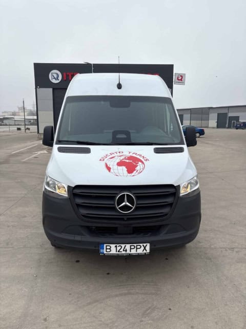 Microbuz Mercedes Sprinter alb de 20 de locuri, văzut din față, cu sigla Ducato Trans pe capotă