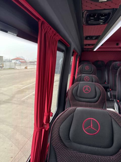 Interiorul microbuzului de 20 de locuri: scaune negre cu sigla Mercedes brodată și perdele roșii