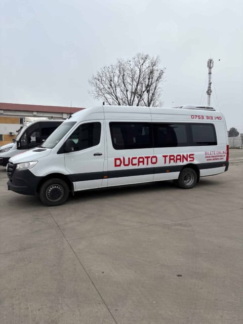 Microbuz Mercedes Sprinter alb de 20 de locuri, din lateral, cu inscripția Ducato Trans