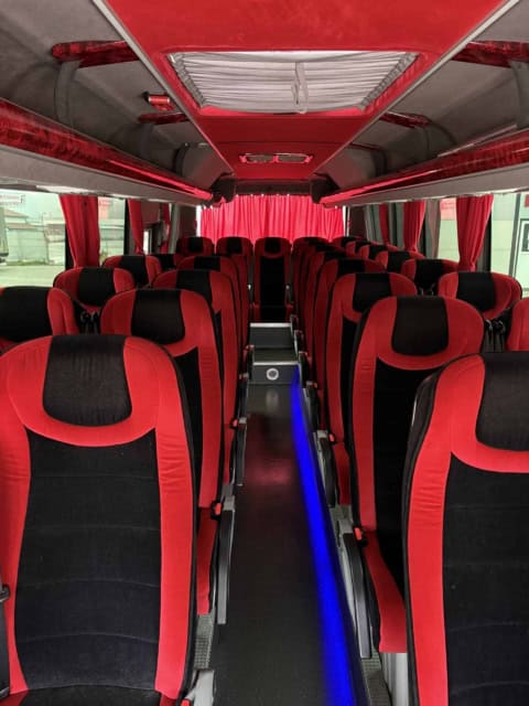Culoarul microbuzului de 30 de locuri, cu lumină albastră pe podea și scaune cu centuri de siguranță